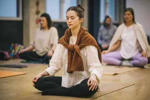 Woman meditating in a yoga class with others.